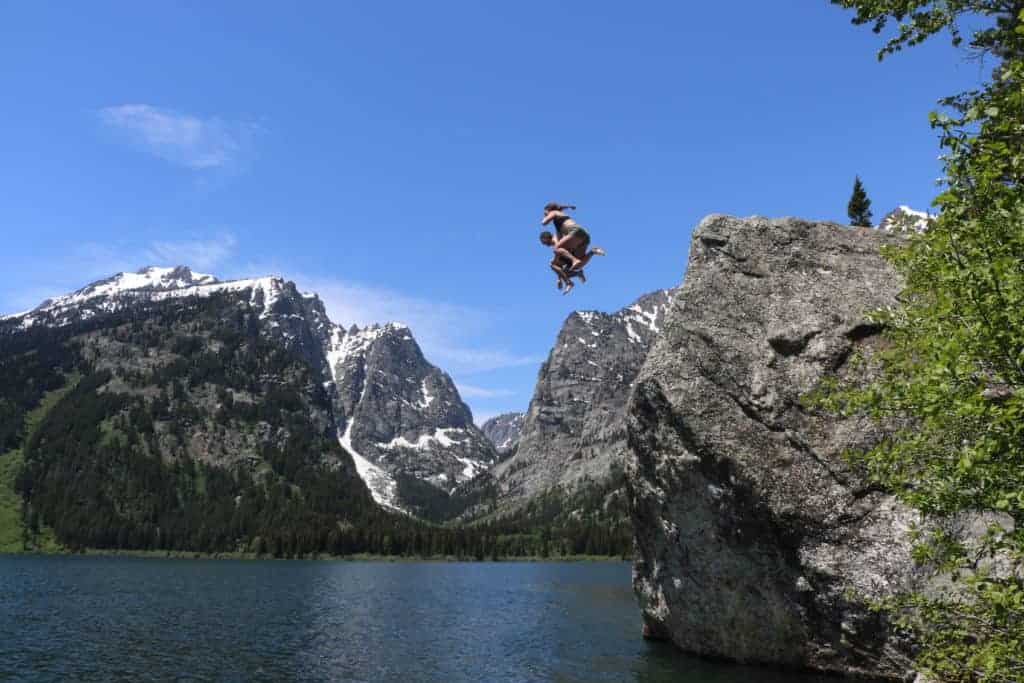 two people jumping off cliff into water