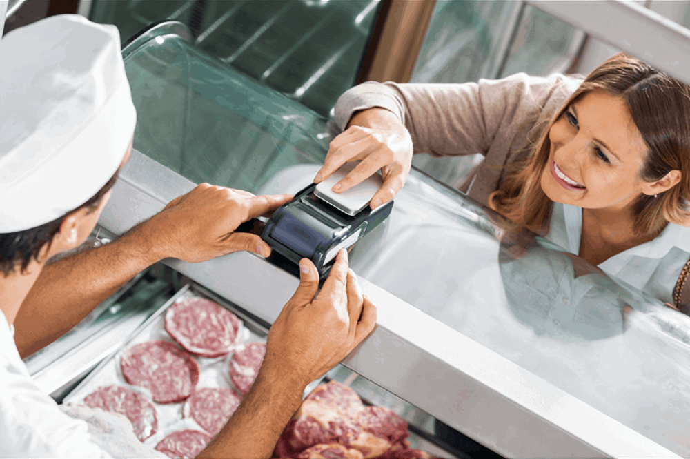 a woman pays a butcher with her smartphone