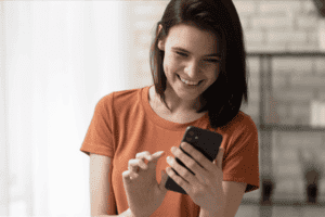 a woman smiles while typing on her smartphone