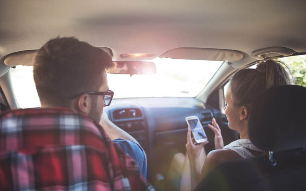 Photo of young couple traveling with cell phone booster for vehicles